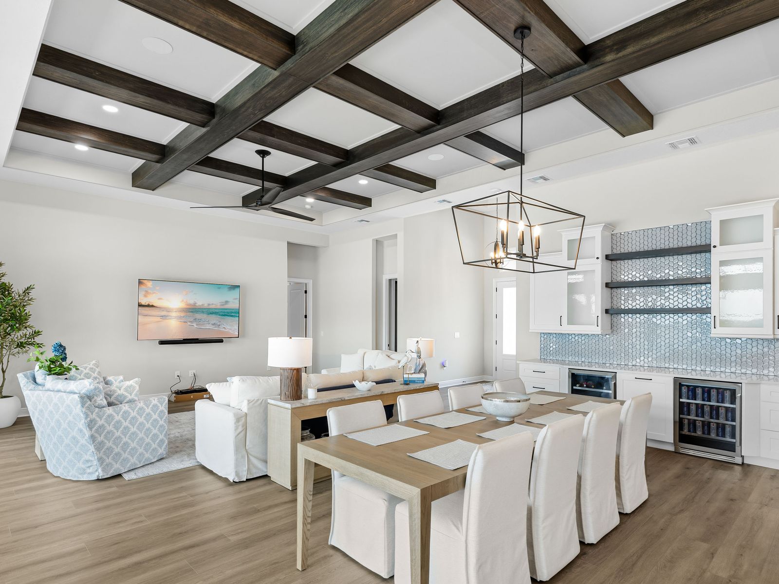 Open kitchen and dining area under a grid of dark crossed beams on a white ceiling with a lantern pendant